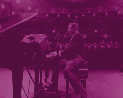 Purple tinted image of Jim Brickman playing on a Grand Piano