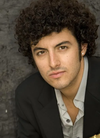 Christopher Coletti, a man with dark curly hair wearing a suit